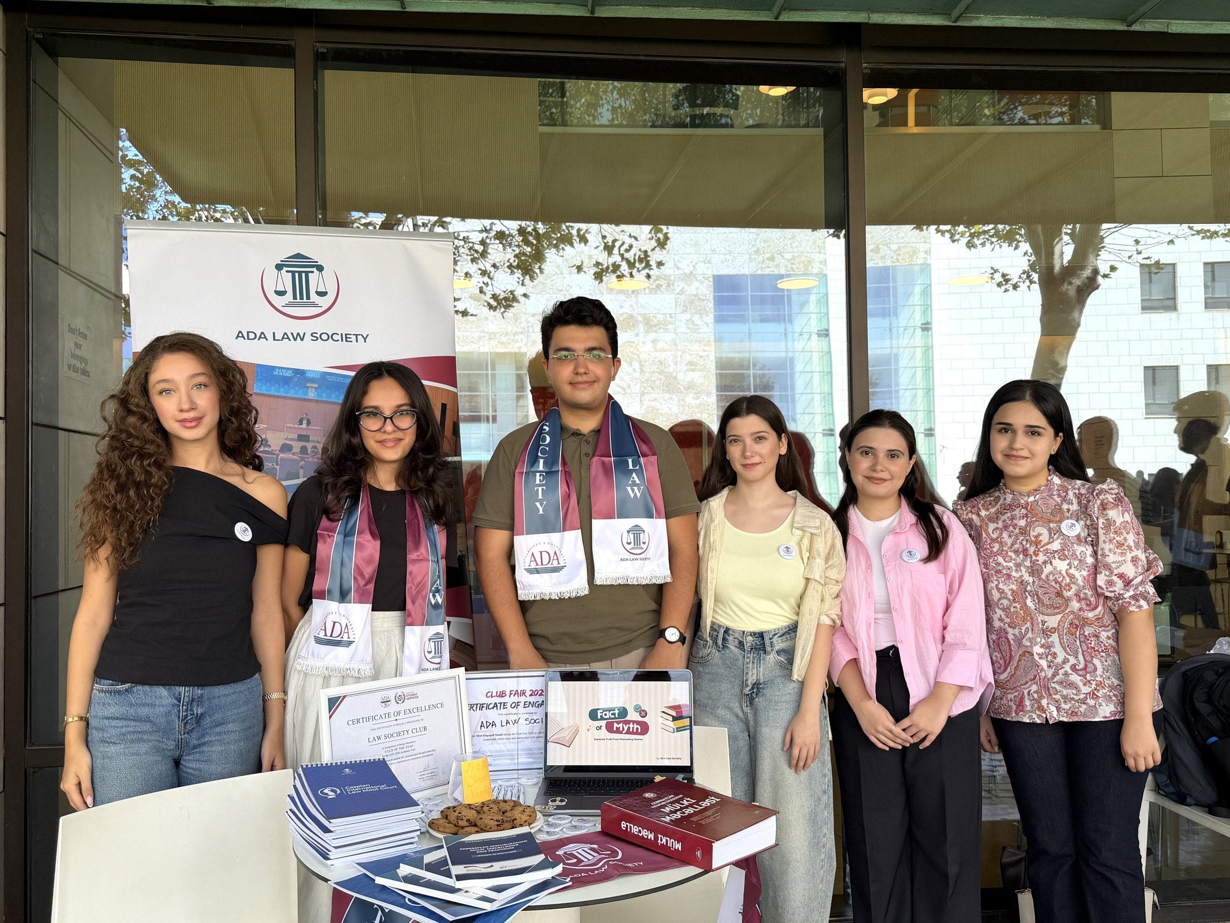 ADA Law Society members standing together at the Society's stand, beside its roll-up banner, at the ADA University orientation fair.